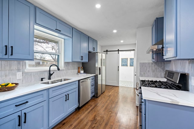 kitchen with blue cabinetry, sink, appliances with stainless steel finishes, dark hardwood / wood-style floors, and a barn door