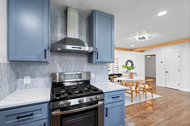 kitchen featuring backsplash, dark hardwood / wood-style floors, stainless steel range with gas stovetop, light stone counters, and wall chimney exhaust hood