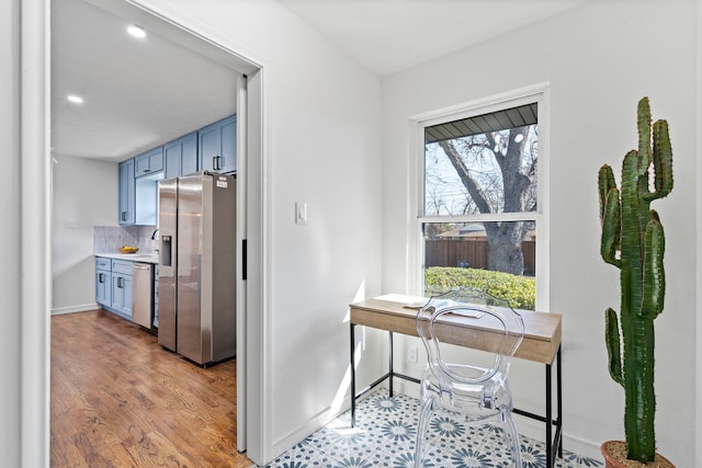 kitchen featuring tasteful backsplash, stainless steel appliances, blue cabinets, and light wood-type flooring