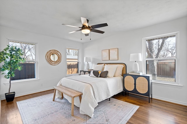 bedroom with hardwood / wood-style flooring, ceiling fan, and multiple windows