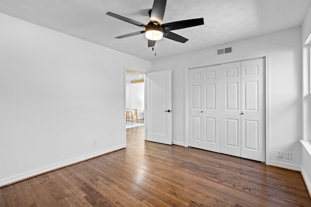 unfurnished bedroom with dark wood-type flooring, ceiling fan, and a closet