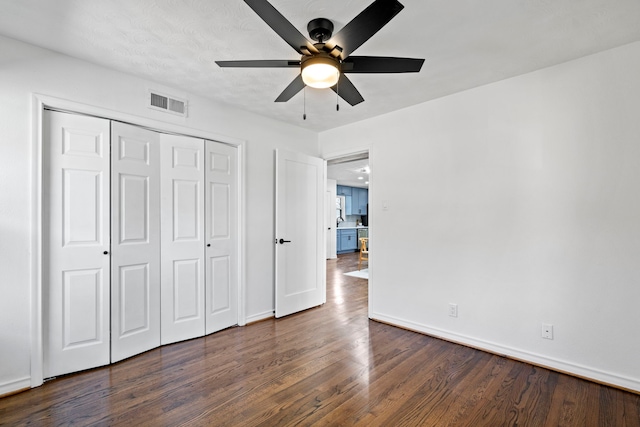 unfurnished bedroom with dark hardwood / wood-style floors, a closet, and ceiling fan