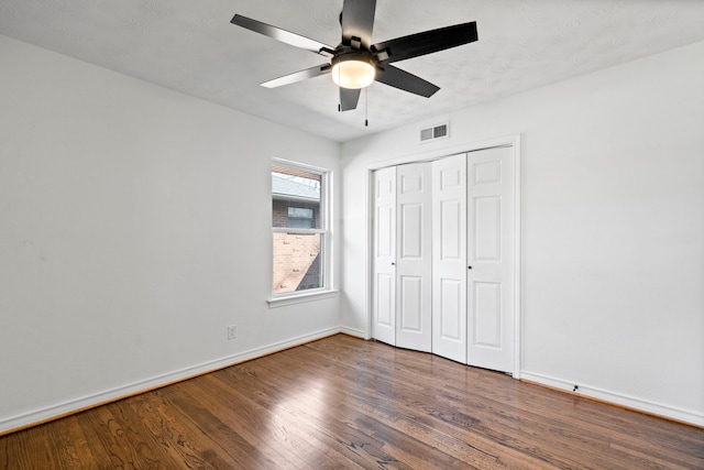 unfurnished bedroom featuring ceiling fan, dark hardwood / wood-style flooring, and a closet