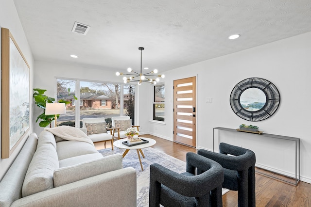 living room with dark wood-type flooring, a chandelier, and a textured ceiling