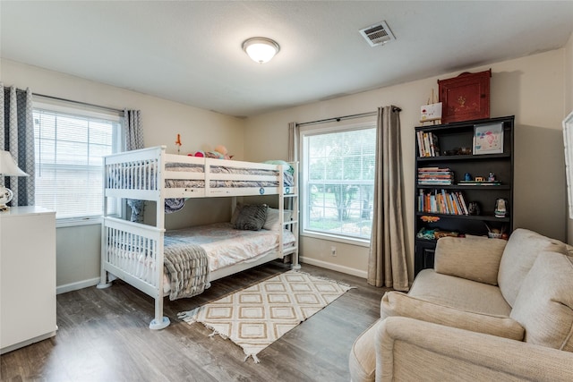 bedroom with multiple windows and dark hardwood / wood-style flooring