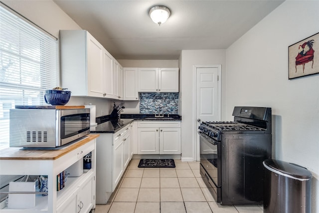 kitchen with gas stove, light tile patterned flooring, white cabinets, and backsplash