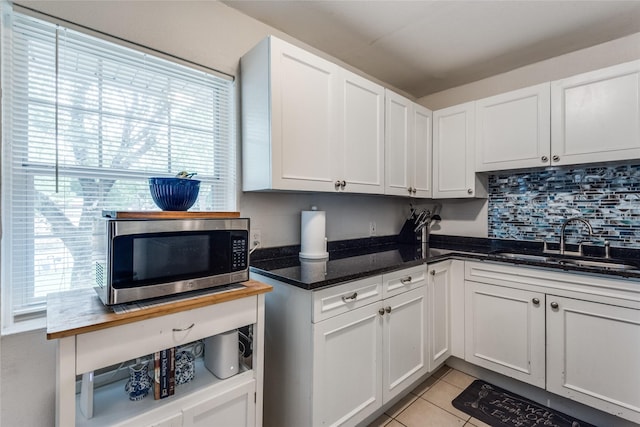 kitchen with sink, light tile patterned floors, and white cabinets