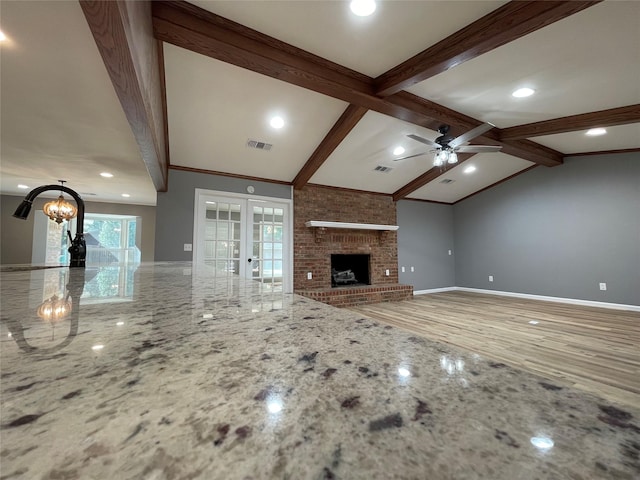 unfurnished living room featuring french doors, sink, vaulted ceiling with beams, a brick fireplace, and ceiling fan