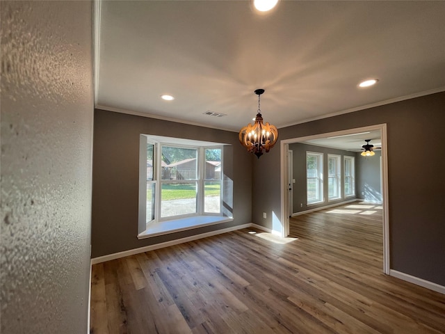 unfurnished dining area with crown molding, hardwood / wood-style flooring, a chandelier, and a healthy amount of sunlight