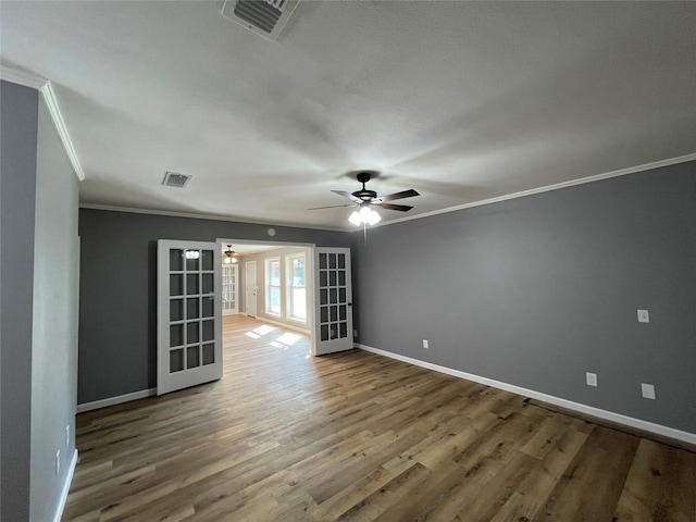 empty room featuring hardwood / wood-style flooring, ornamental molding, ceiling fan, and french doors