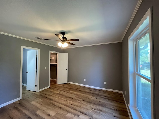 unfurnished bedroom featuring a spacious closet, ornamental molding, a closet, ceiling fan, and hardwood / wood-style floors