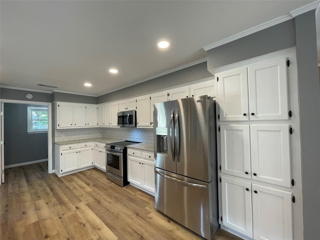 kitchen with tasteful backsplash, ornamental molding, appliances with stainless steel finishes, and white cabinets