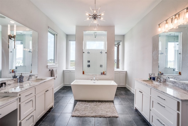 bathroom featuring vanity, a tub, a healthy amount of sunlight, and an inviting chandelier