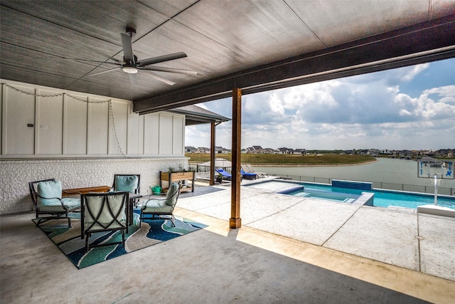 view of pool with ceiling fan, a patio, a water view, and an in ground hot tub