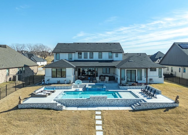 rear view of house with a lawn, a patio area, and a pool with hot tub