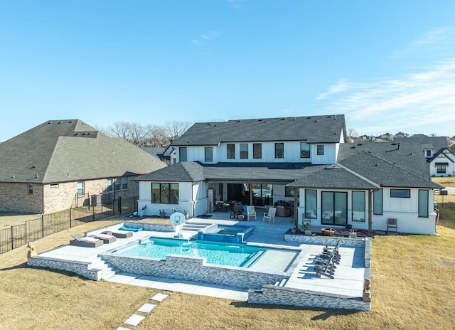 back of house featuring a swimming pool with hot tub, a patio area, and a lawn