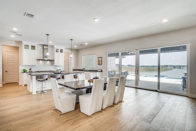 dining room featuring french doors, a water view, a textured ceiling, and light wood-type flooring