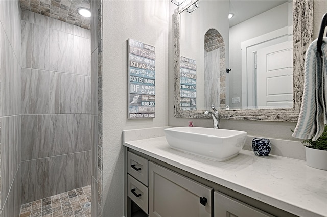 bathroom with tiled shower and vanity