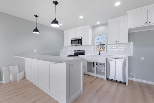 kitchen with appliances with stainless steel finishes, white cabinetry, backsplash, hanging light fixtures, and light wood-type flooring