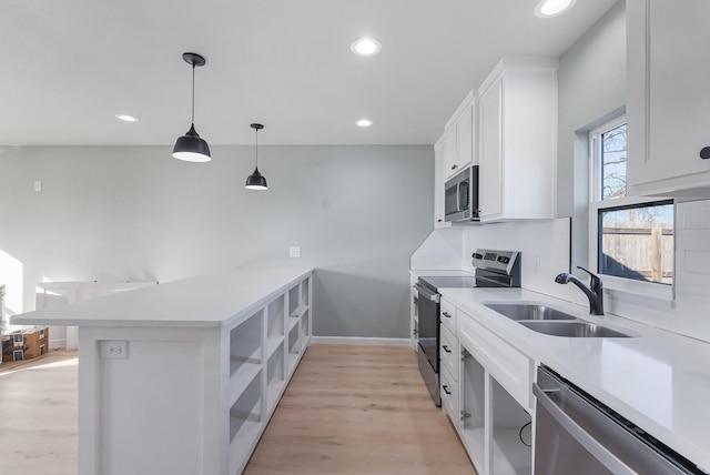 kitchen with white cabinetry, sink, kitchen peninsula, stainless steel appliances, and light hardwood / wood-style flooring