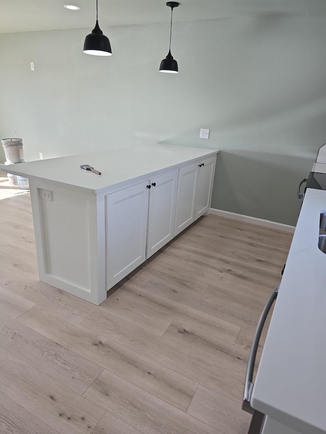 kitchen featuring white cabinetry, pendant lighting, kitchen peninsula, and light hardwood / wood-style flooring