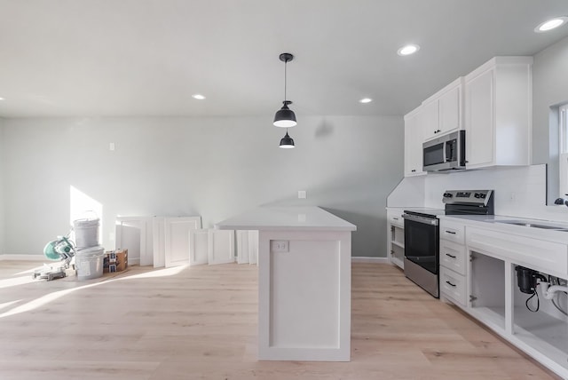 kitchen with sink, light hardwood / wood-style flooring, appliances with stainless steel finishes, white cabinets, and a kitchen island