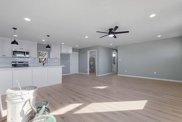 kitchen with appliances with stainless steel finishes, white cabinetry, backsplash, hanging light fixtures, and light hardwood / wood-style flooring