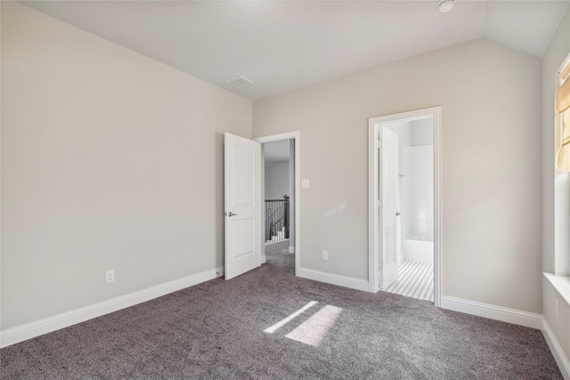 unfurnished bedroom featuring dark carpet and vaulted ceiling