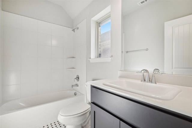 full bathroom with tiled shower / bath, vanity, toilet, and lofted ceiling