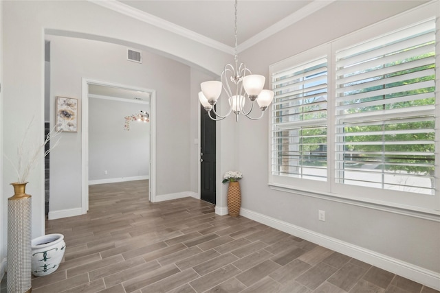 unfurnished dining area featuring crown molding, an inviting chandelier, and hardwood / wood-style floors