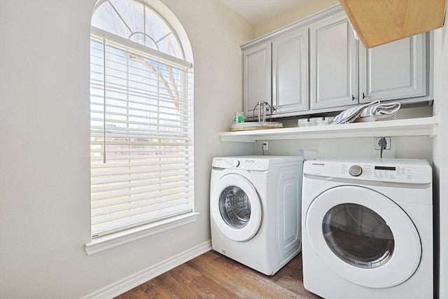 laundry room with cabinet space, baseboards, washer and clothes dryer, and wood finished floors