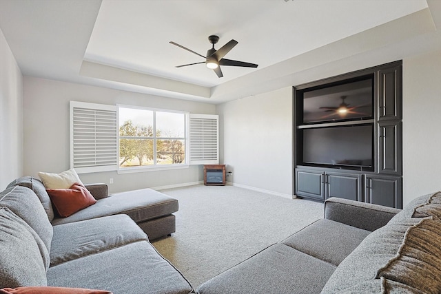 carpeted living area featuring ceiling fan, baseboards, and a raised ceiling