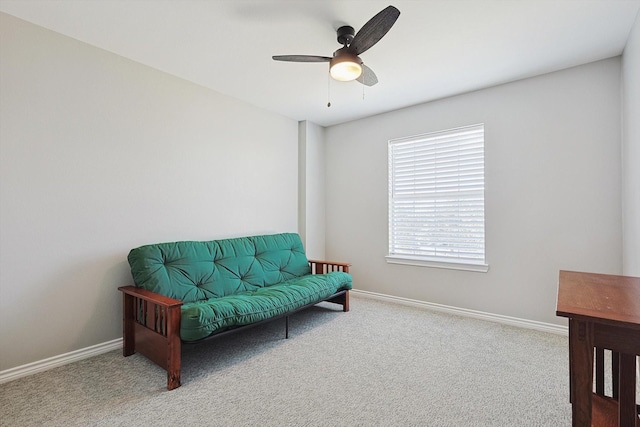 sitting room featuring carpet, baseboards, and a ceiling fan