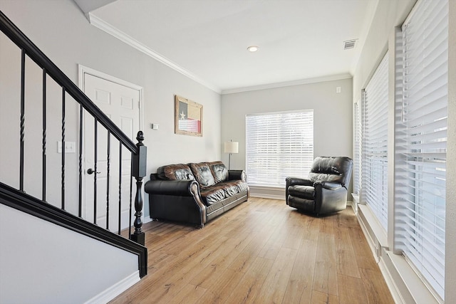 living area featuring baseboards, visible vents, stairs, crown molding, and light wood-style floors