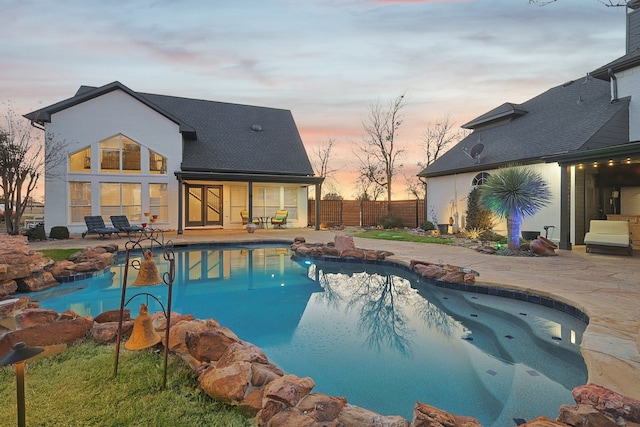 pool at dusk featuring a fenced in pool, a patio area, and fence