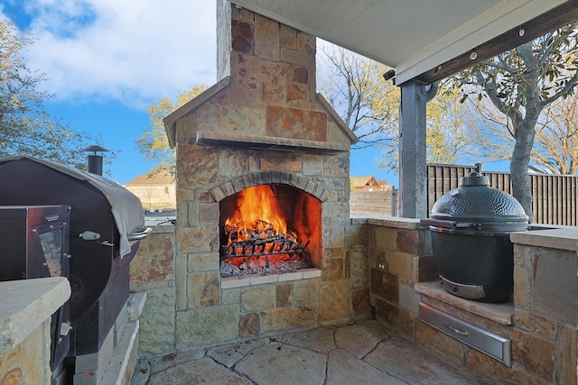 view of patio / terrace featuring an outdoor stone fireplace and grilling area