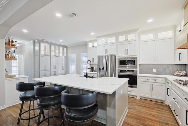 kitchen featuring light wood finished floors, a center island with sink, visible vents, appliances with stainless steel finishes, and a sink