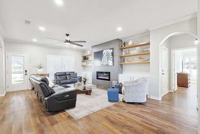 living area with arched walkways, a fireplace, wood finished floors, and visible vents