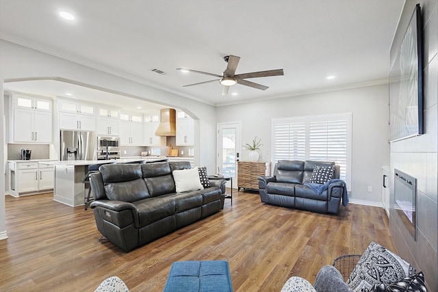 living room featuring visible vents, crown molding, arched walkways, and wood finished floors