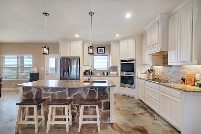 kitchen featuring stainless steel appliances, sink, an island with sink, and white cabinets