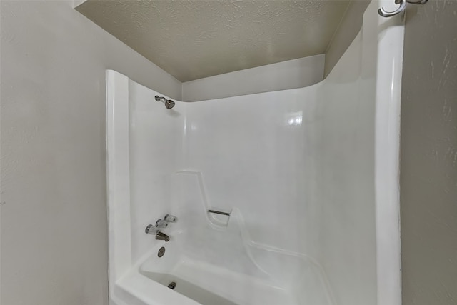 bathroom featuring shower / bathtub combination and a textured ceiling