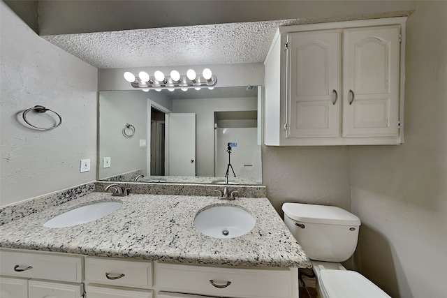 bathroom featuring vanity, toilet, and a textured ceiling