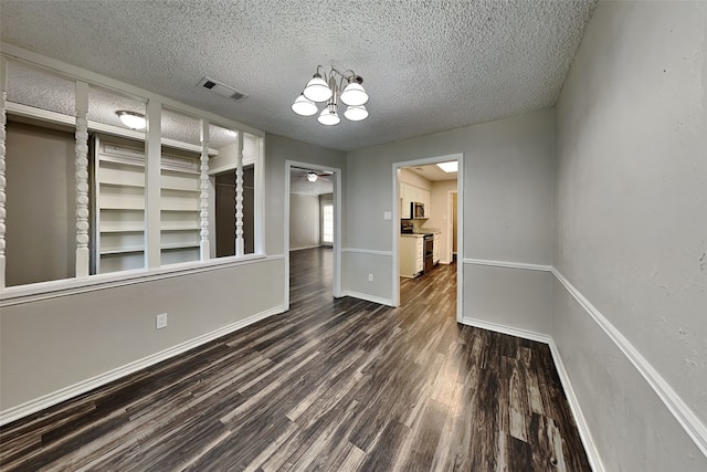 unfurnished dining area with ceiling fan with notable chandelier, dark hardwood / wood-style floors, and a textured ceiling