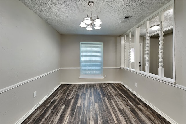 spare room featuring a notable chandelier, dark hardwood / wood-style floors, and a textured ceiling