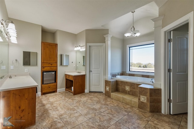 bathroom with decorative columns, tiled bath, tile patterned flooring, vanity, and a notable chandelier