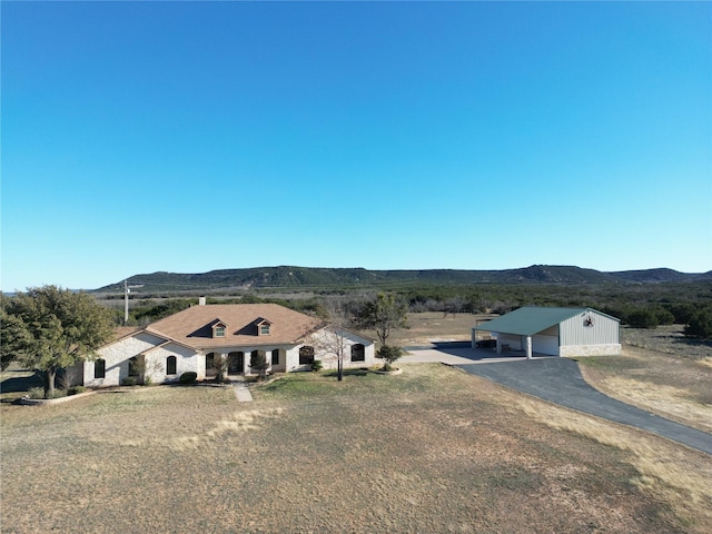 view of front of property with a garage, a mountain view, a front yard, and an outdoor structure