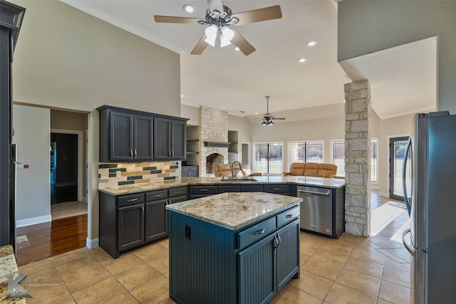 kitchen with sink, kitchen peninsula, a kitchen island, stainless steel appliances, and backsplash