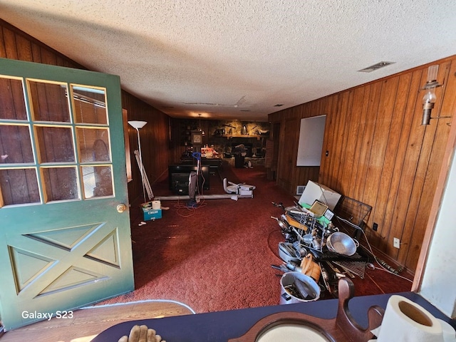 misc room with wooden walls, a textured ceiling, and carpet