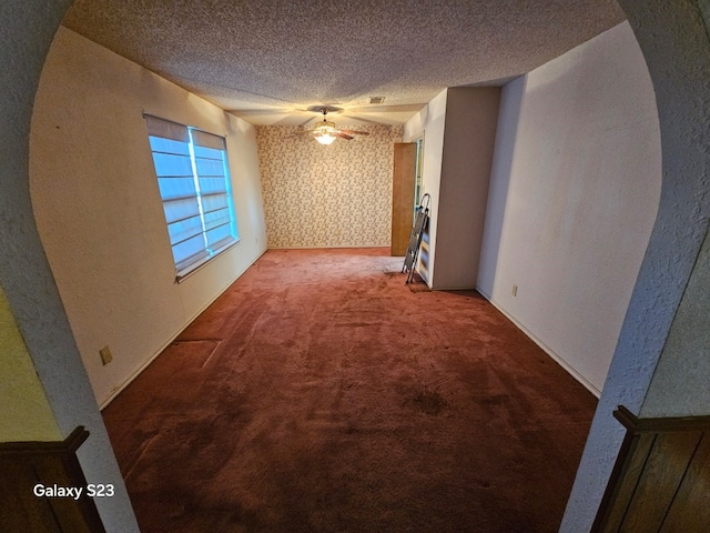 carpeted empty room featuring ceiling fan and a textured ceiling