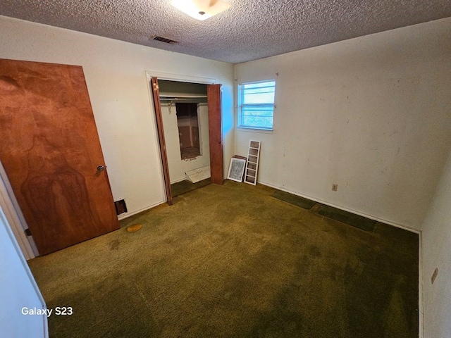 unfurnished bedroom with dark carpet, a textured ceiling, and a closet